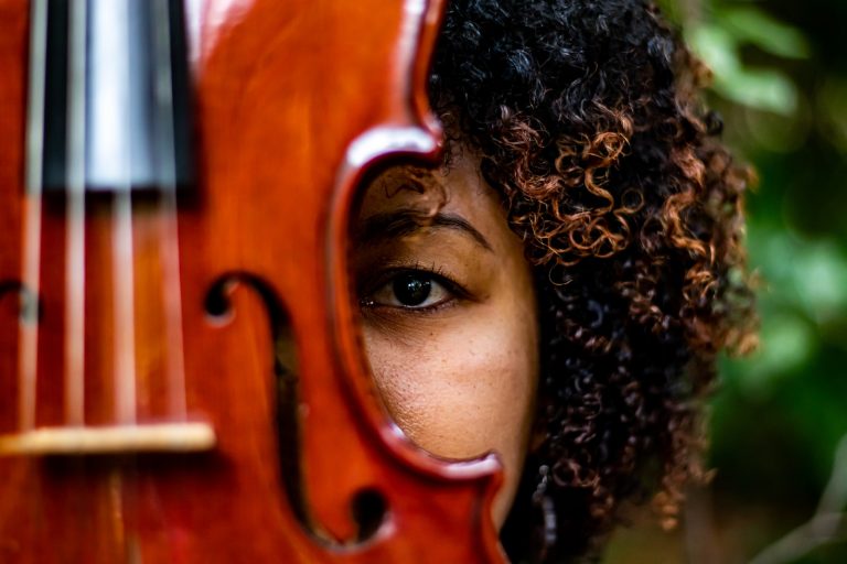 woman with curly hair and brown wooden violin
